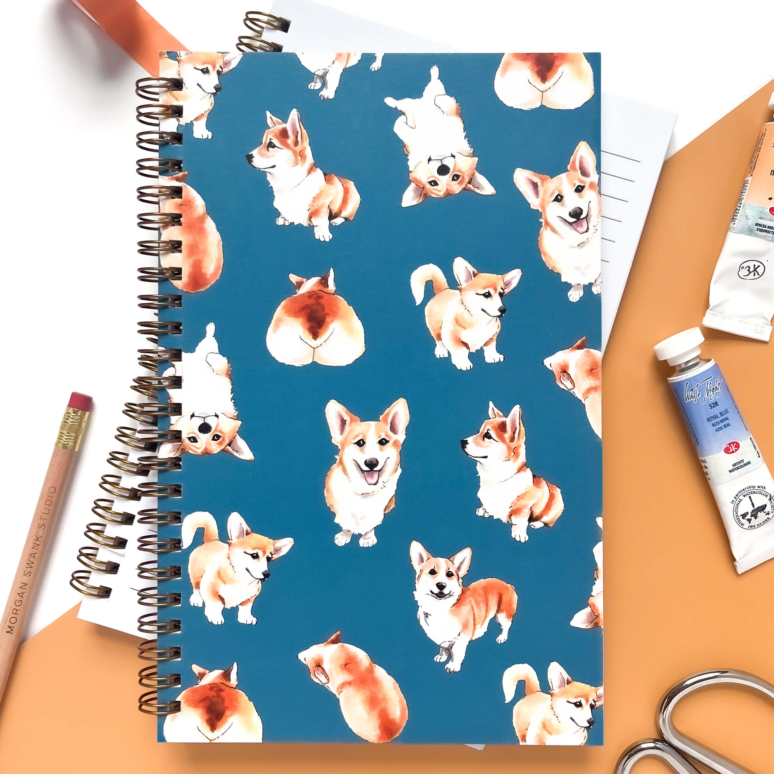 Notebook with marker illustrations of corgis on a teal background.