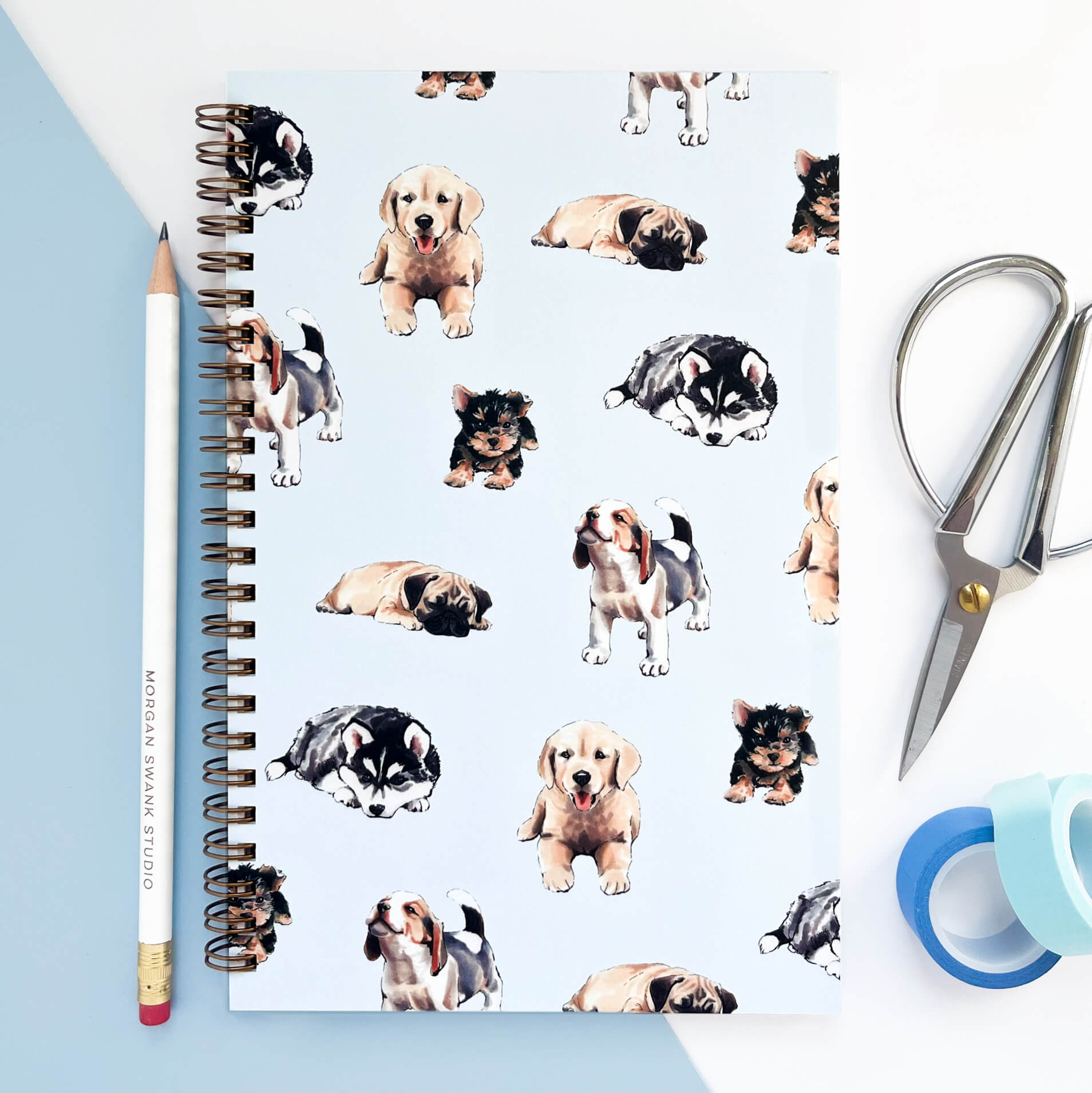 Notebook with illustrated puppies on a pale blue background.