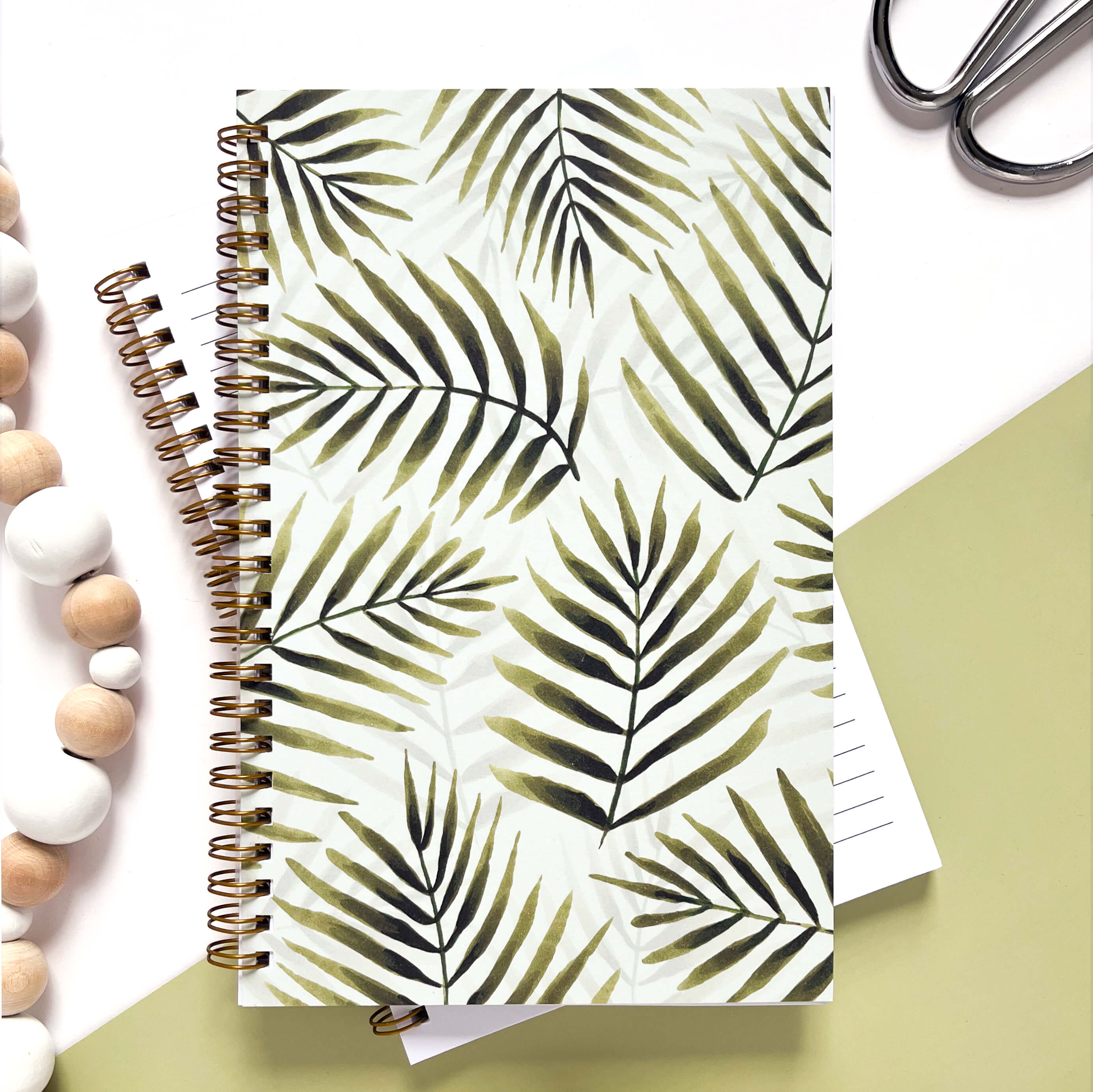Notebook with watercolor green palm leaves on a light green background.