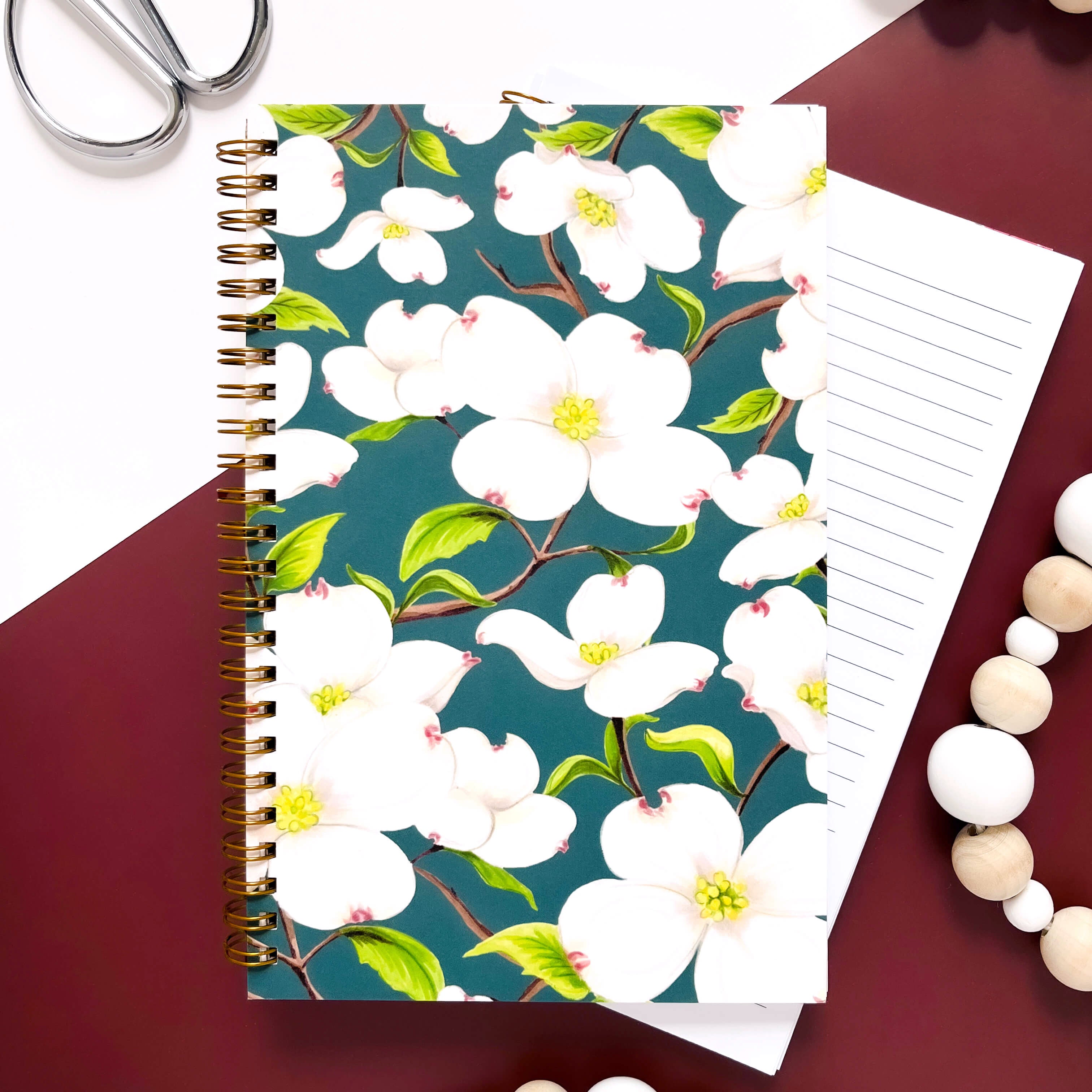 Notebook with white dogwood flowers on a dark green background.