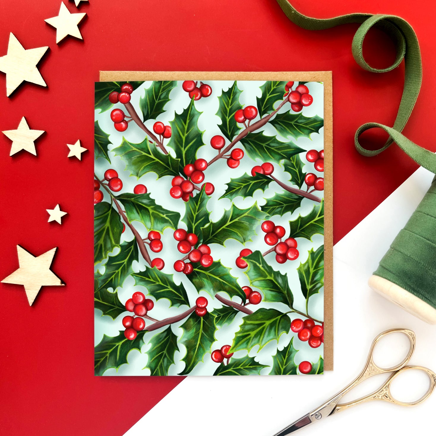 Christmas card with a seamless pattern of green holly leaves and bright red berries on a soft blue background.