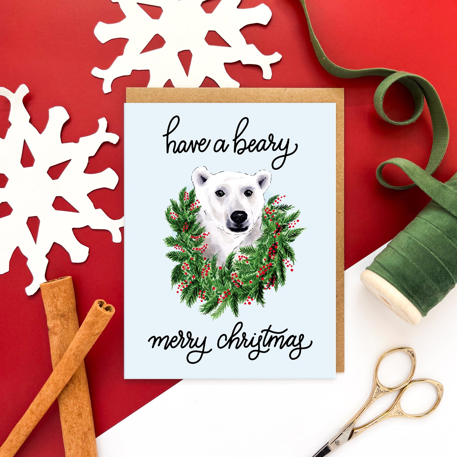 Christmas card with illustrated polar bear in a holiday wreath and the text 'have a beary merry Christmas' on a light blue background.