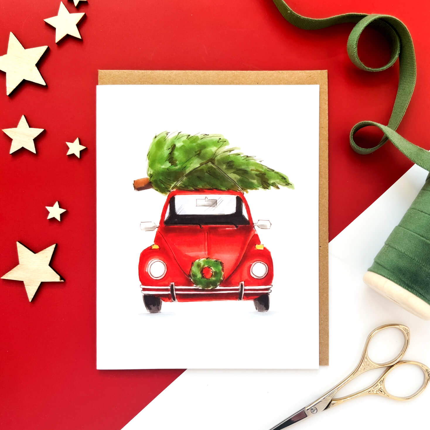 Christmas card with a red vintage car carrying a Christmas tree on the roof and a wreath on the front bumper.