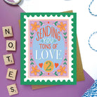 Greeting card with a vintage-inspired postage stamp design featuring flowers and "Sending You Tons of Love" message.