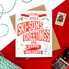 Holiday card with retro typography reading “Apres Ski-sons Greetings and Happy Holidays.”